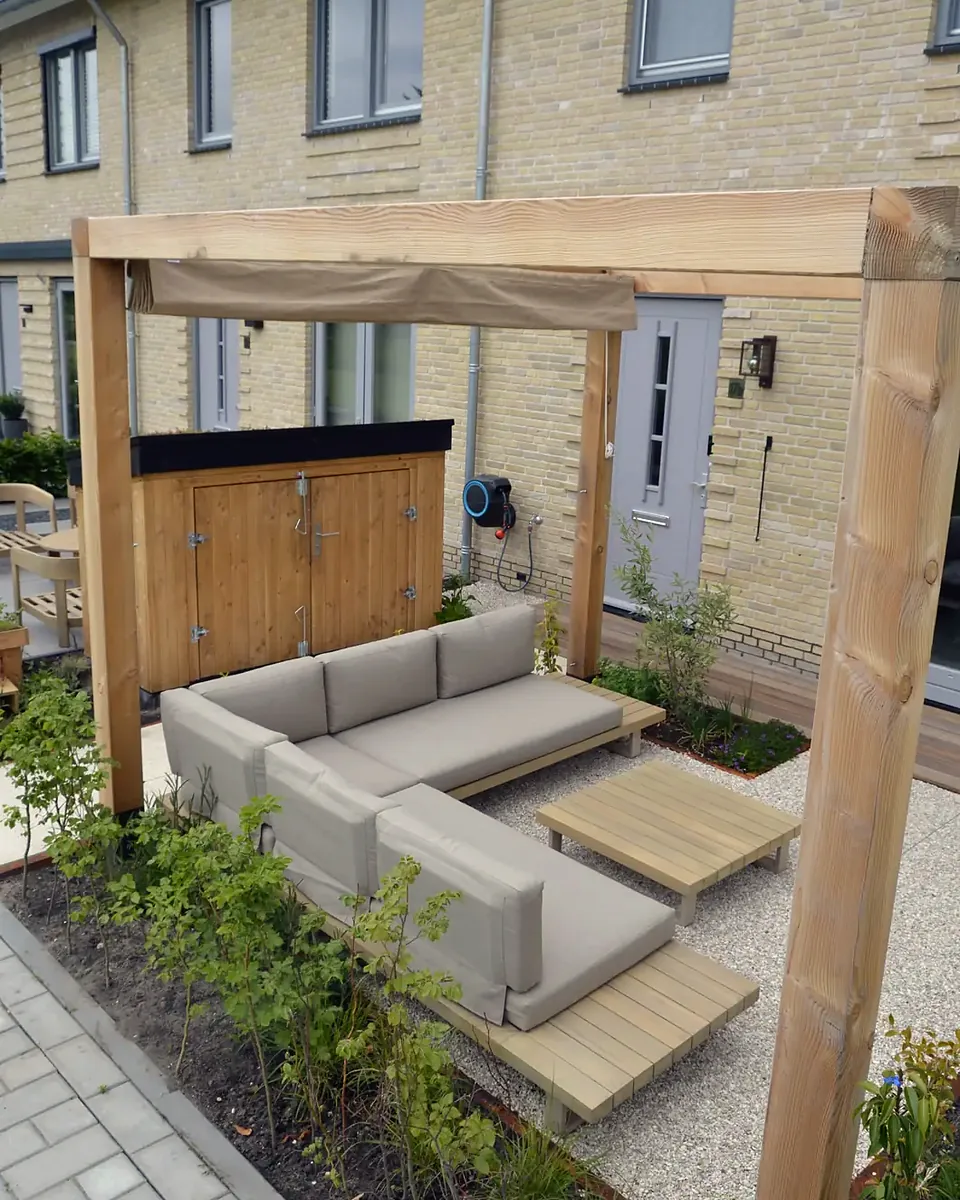 Ná: houten pergola met zithoek op grind voor de achtergevel
