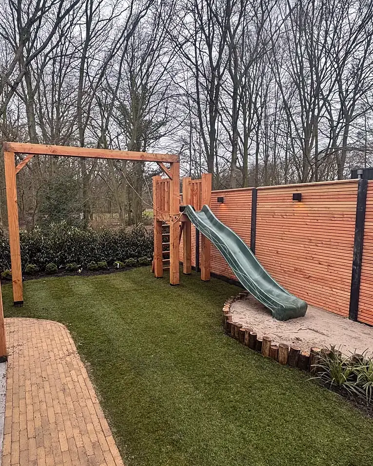 Ná: klinkerpad en gazon naar de speelhoek met schommel en glijbaan