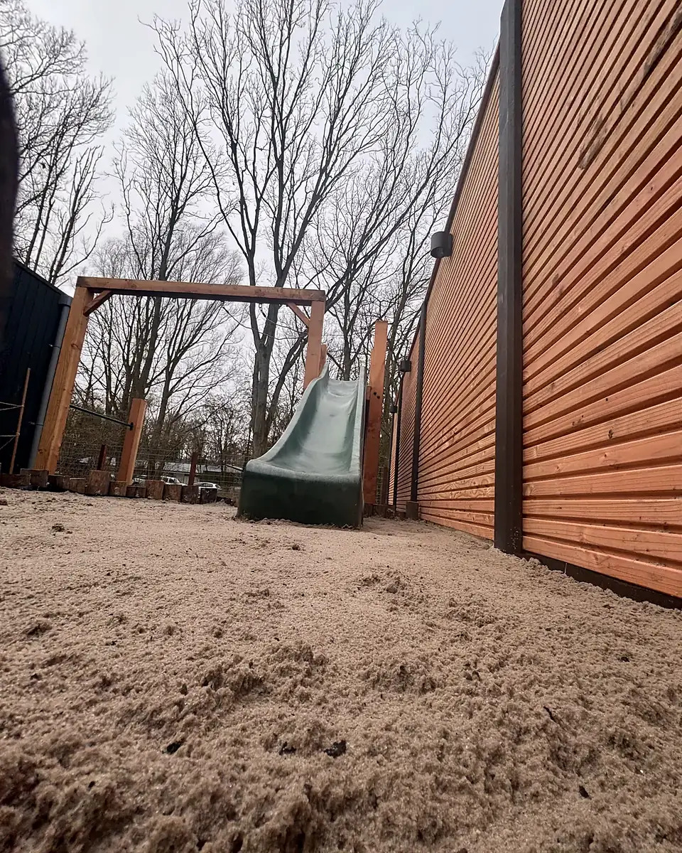 Vóór: zand voor de speelhoek met schommel en glijbaan