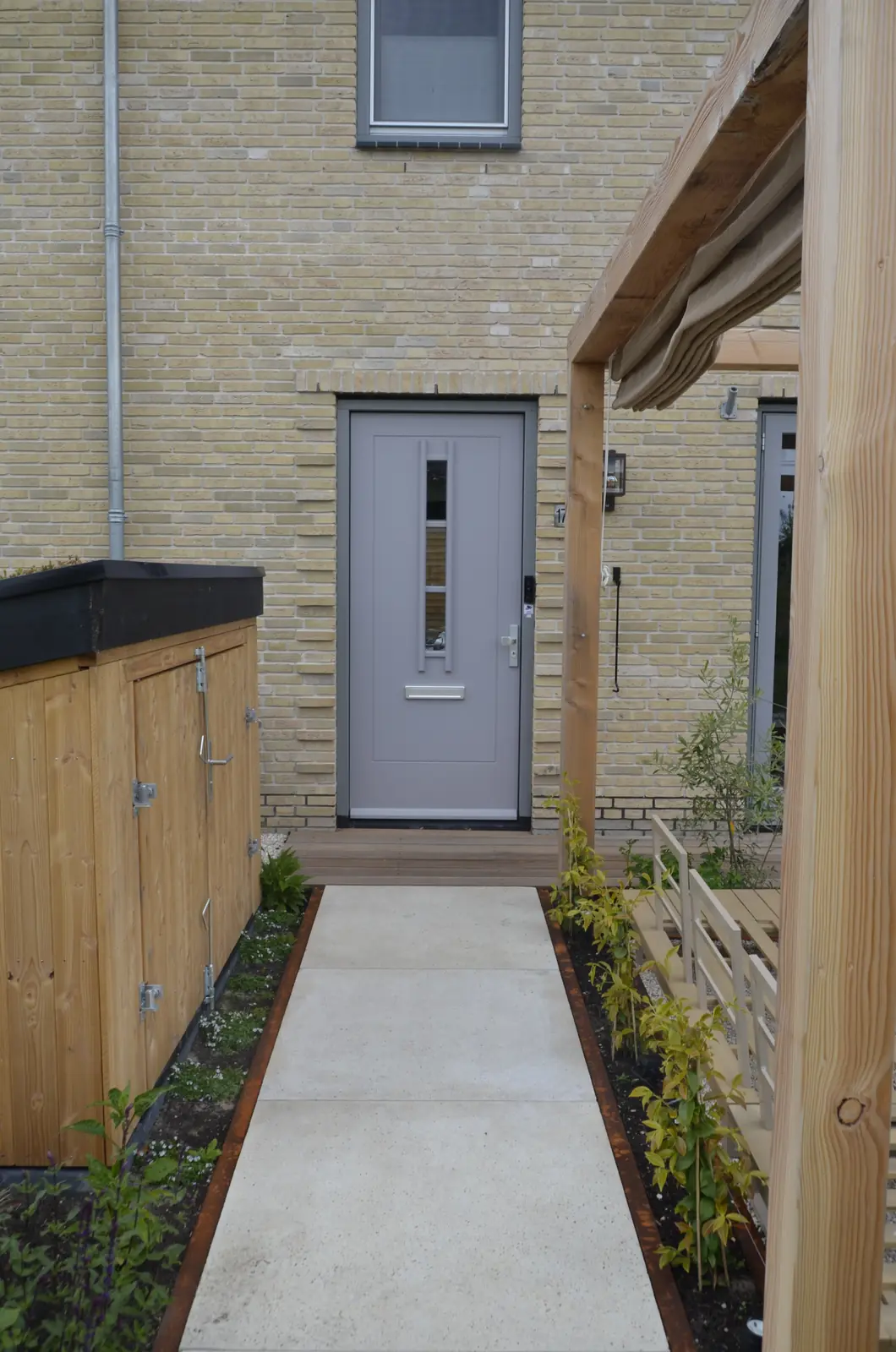 Pergola en zithoek langs de gevel van de nieuwbouwwoning