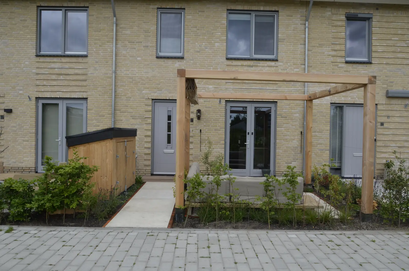 De voorzijde met pergola en het pad naar de voordeur