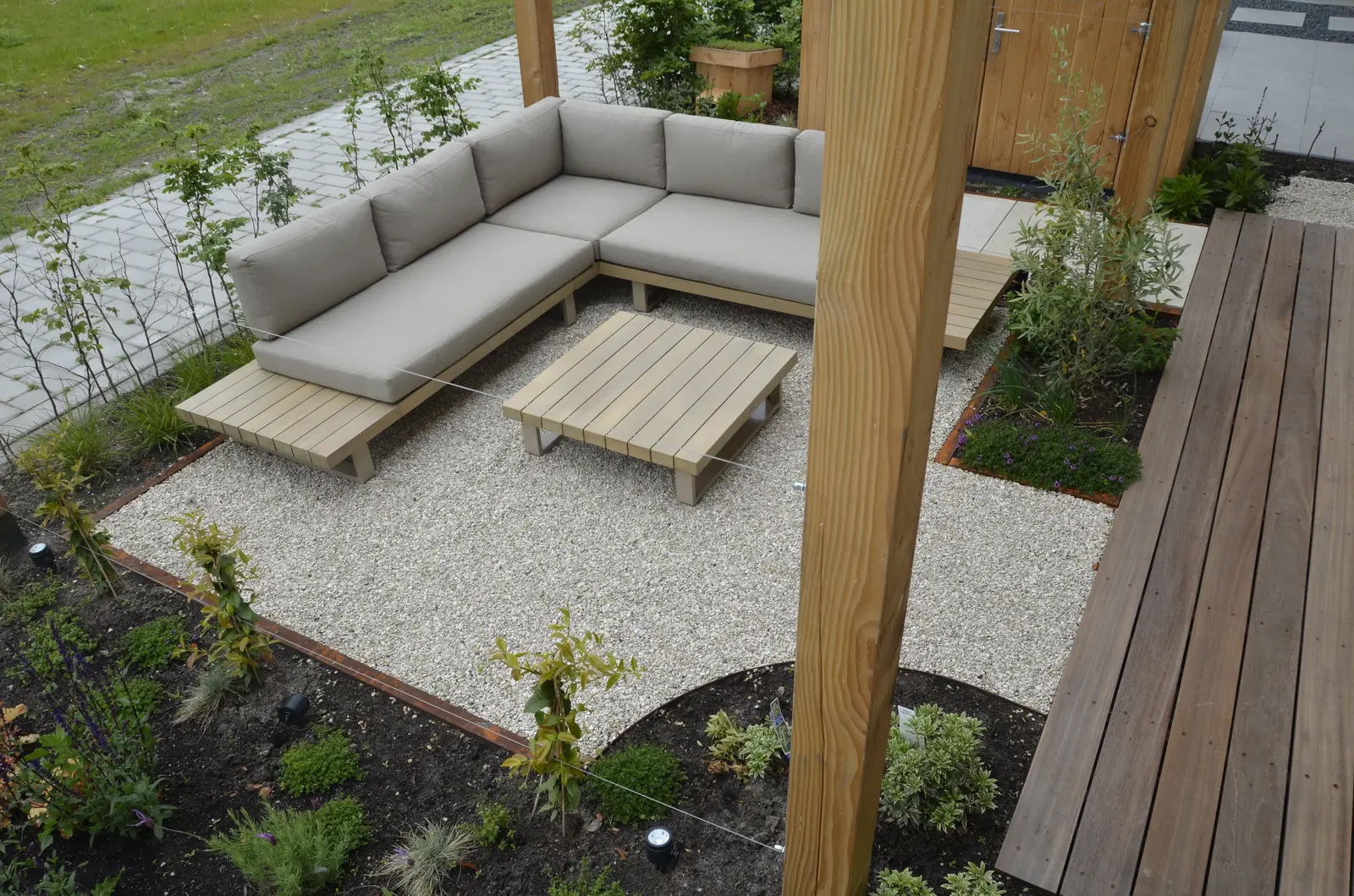Overzicht van de tuin met grind, vlonder en zithoek
