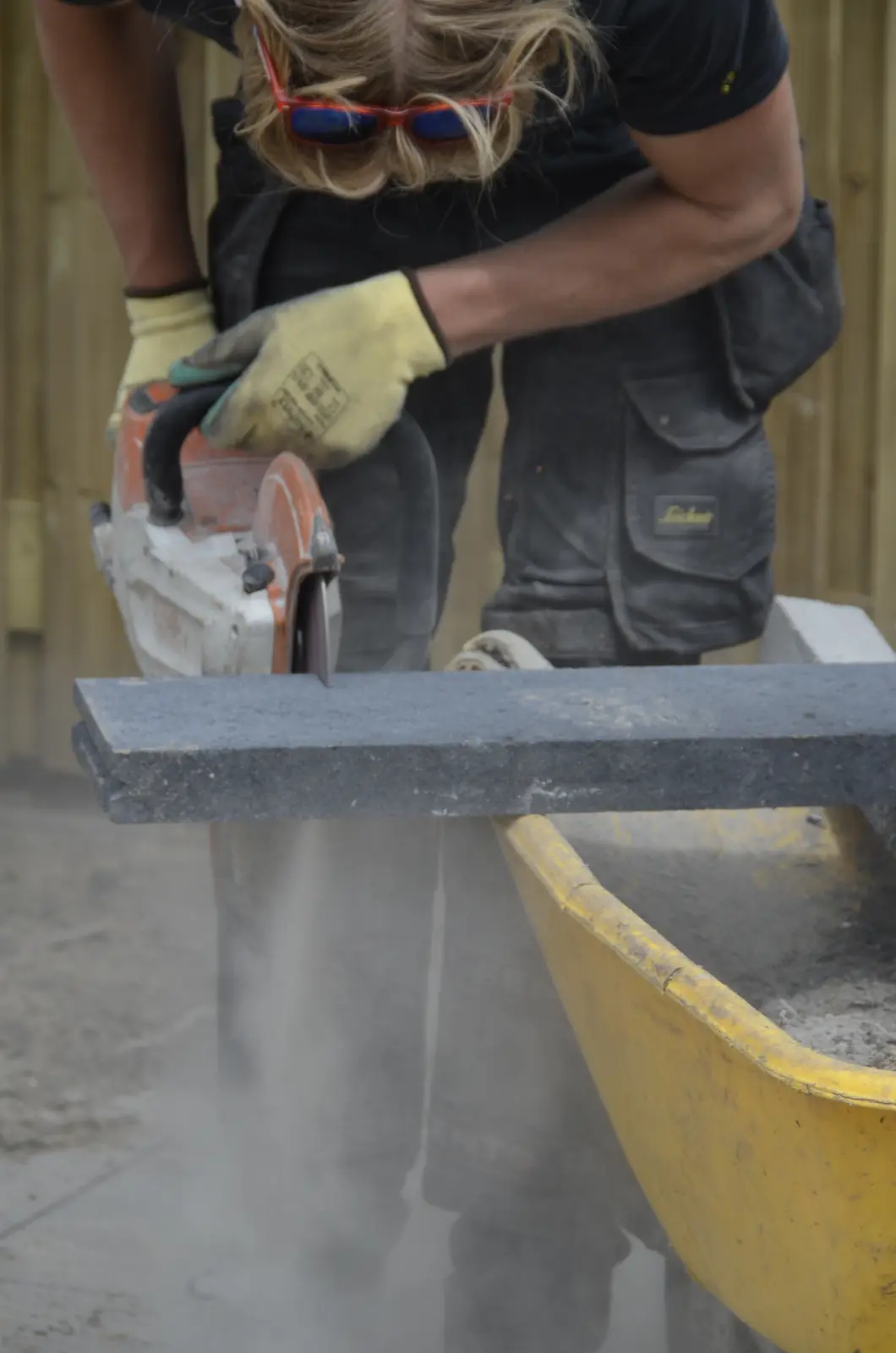 Hovenier zaagt een betonband op maat met de slijptol