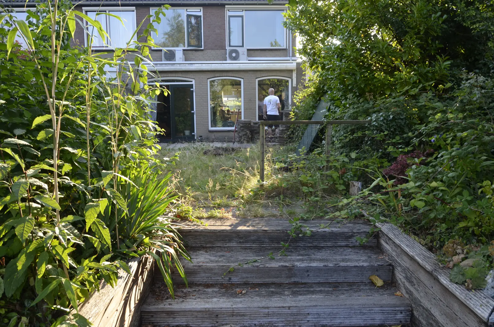 De verwilderde tuin gezien vanaf de woning