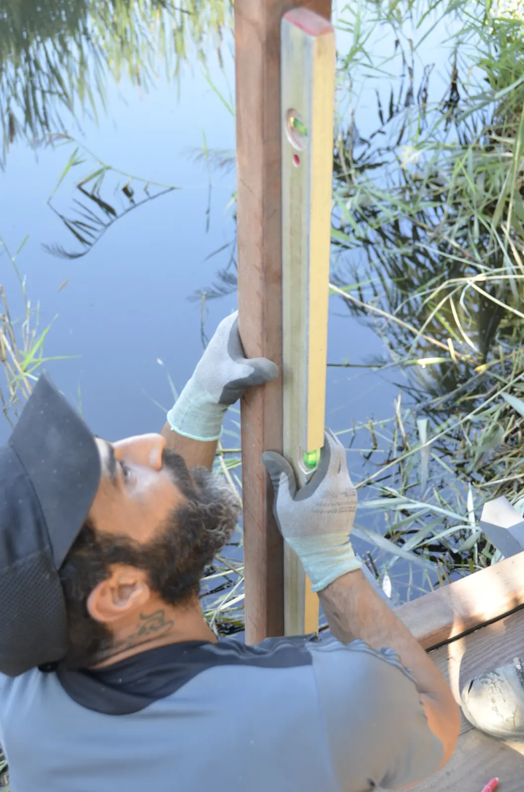 Hovenier zet een paal in het water voor de steiger