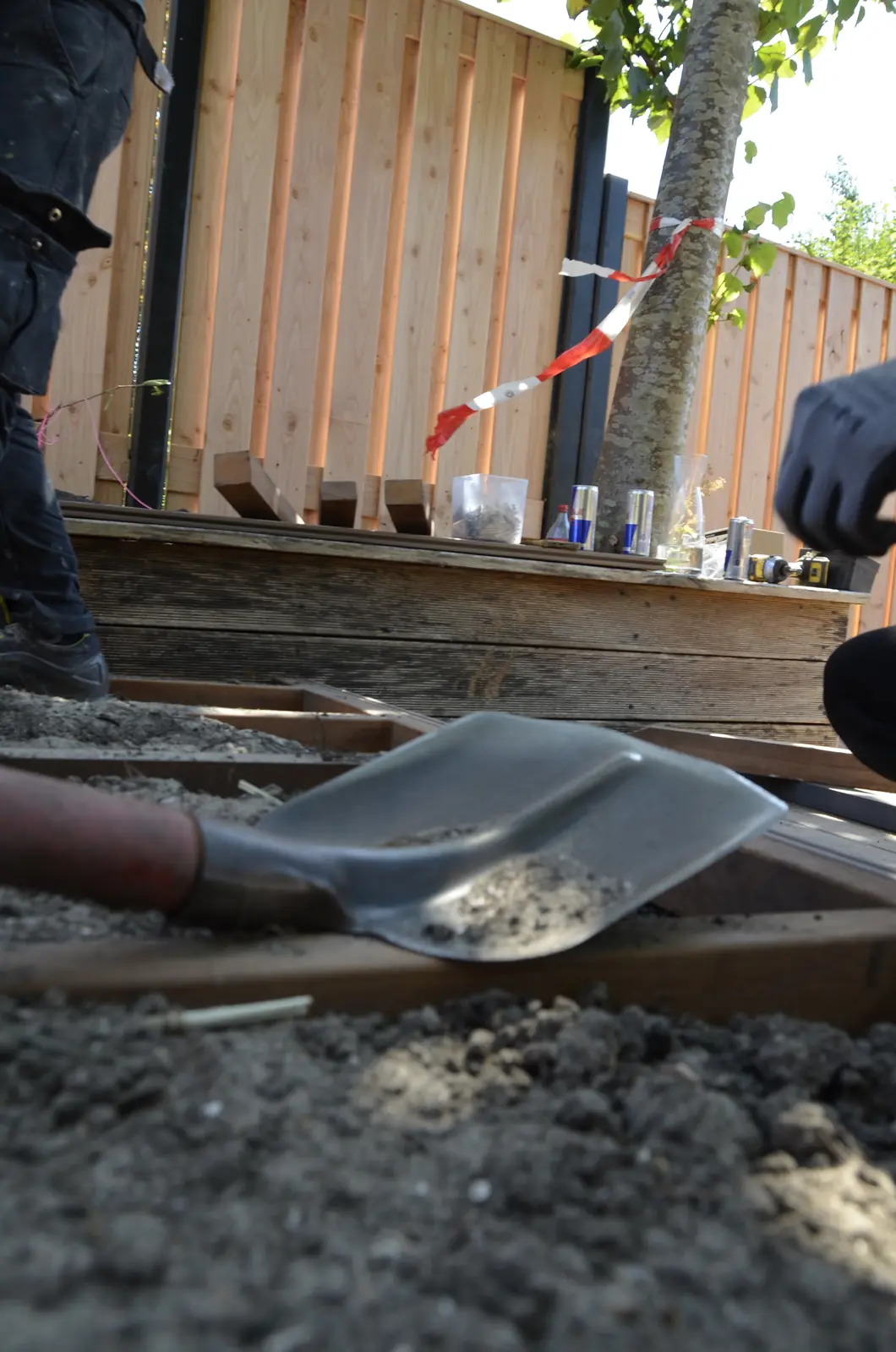 Hovenier schept zand tegen de nieuwe schutting