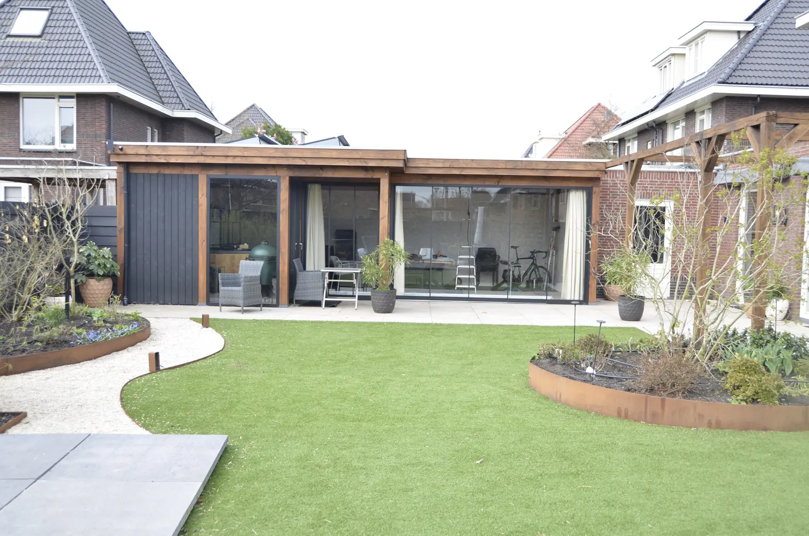 Cortenstalen keerwand langs een bed van wit siergrind