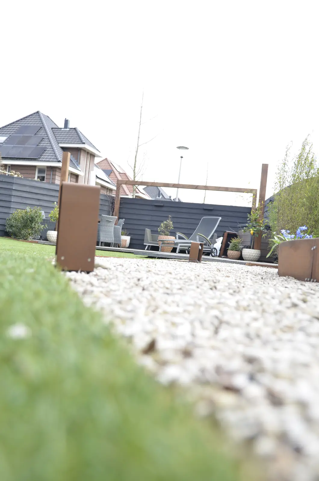Doorkijk onder de douglas overkapping over het gazon naar het terras