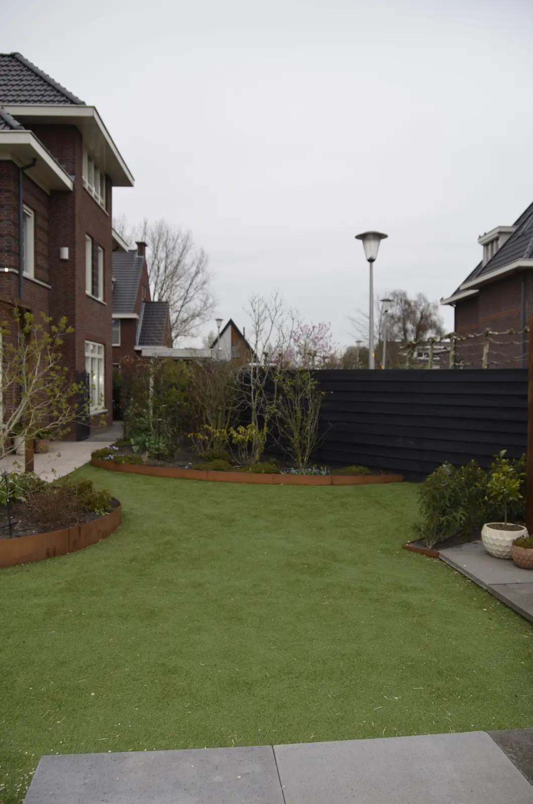 De tuin als zandvlakte, met de bestaande beplanting langs de rand