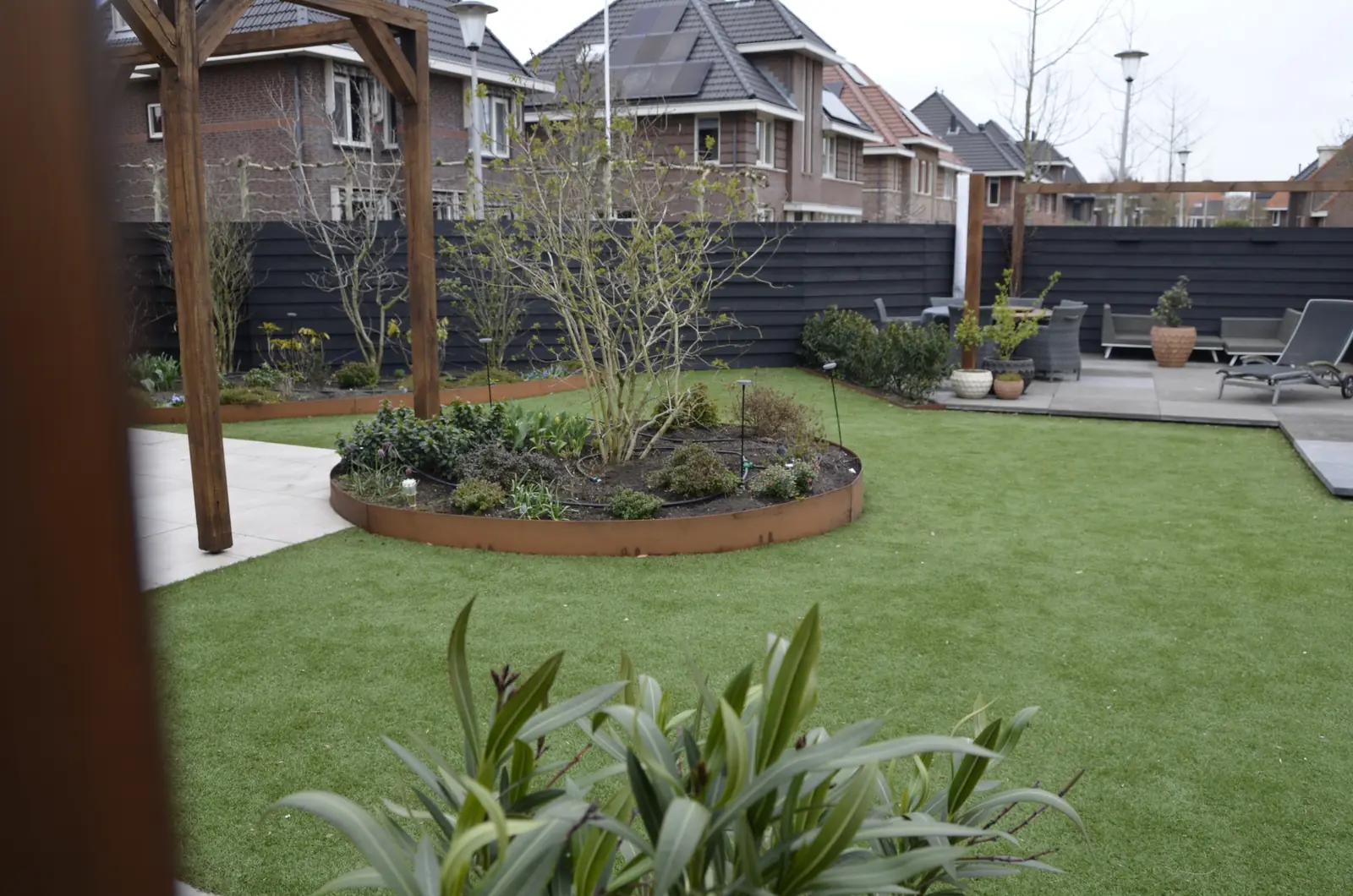 Zand en stapels tegels, met de minigraafmachine achter in de tuin