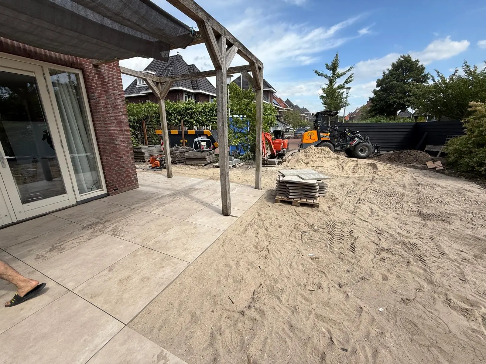 Zand en tegels met de woning erachter