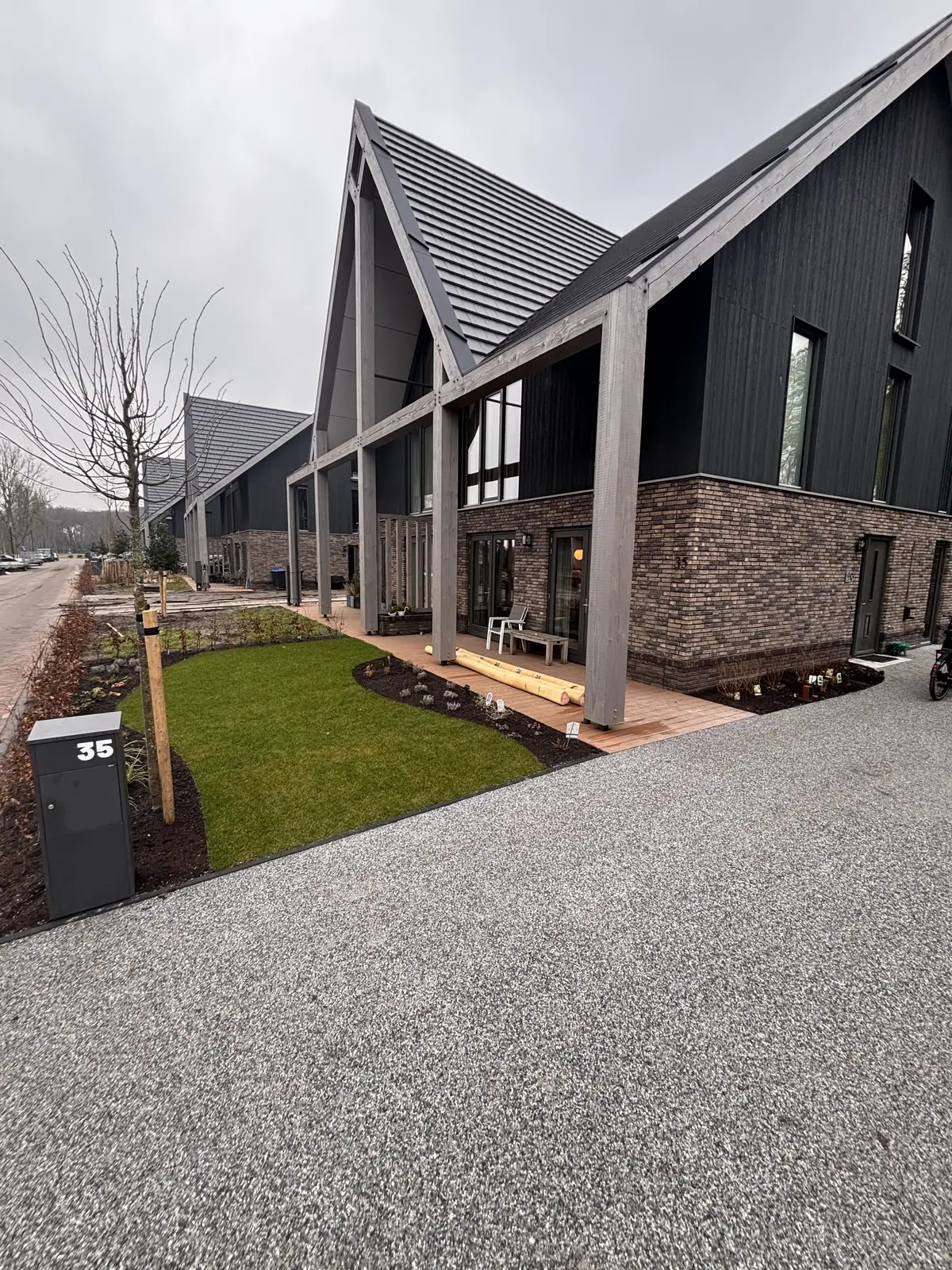 Voortuin met gazon en grind langs de gevel van de nieuwbouwwoning