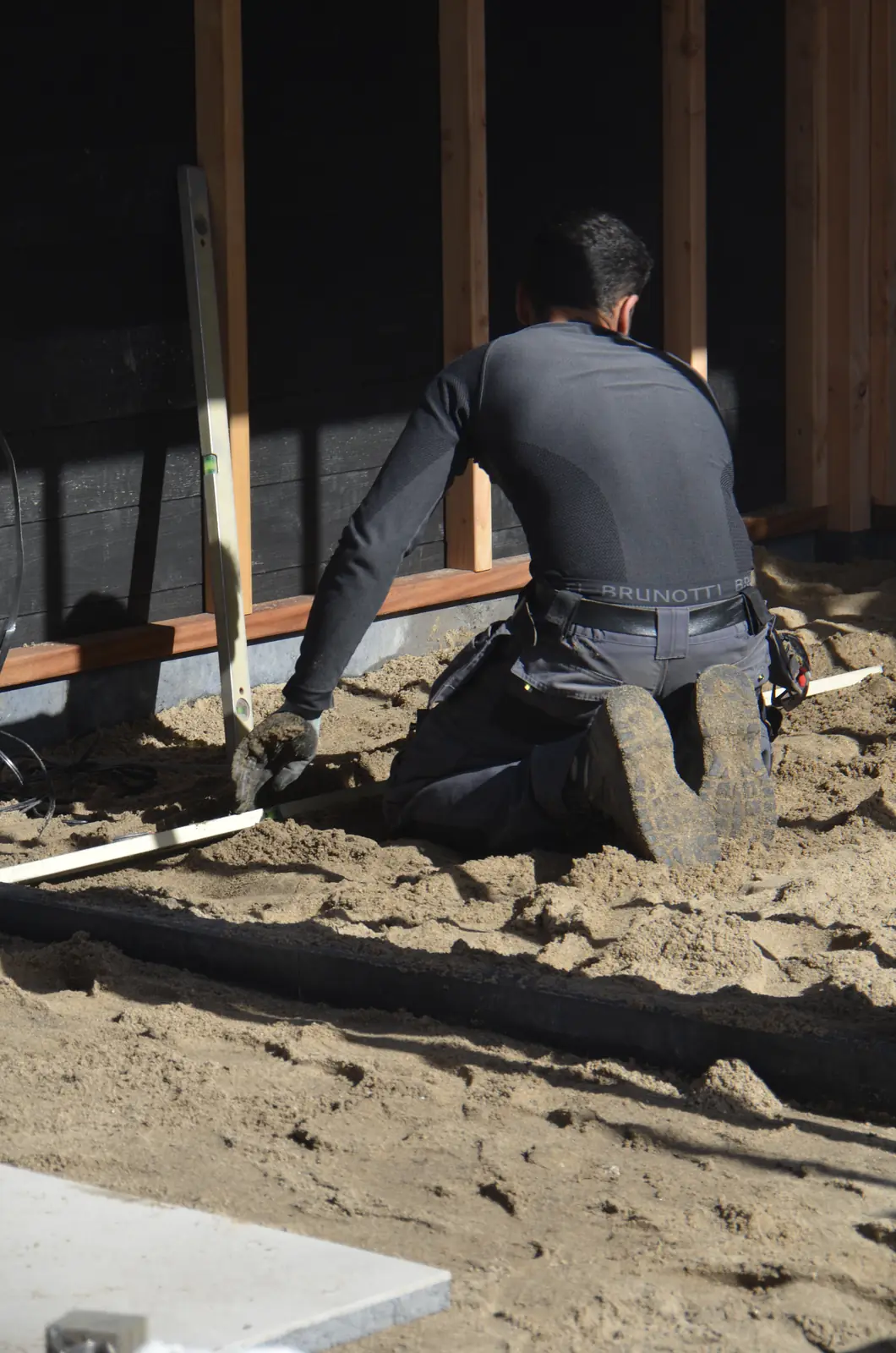 Hovenier reit het zandbed af in het tuinhuis