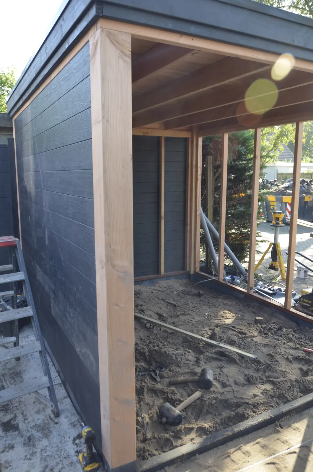 Tuinhuis in aanbouw, met zwarte gevelbekleding en een open voorzijde