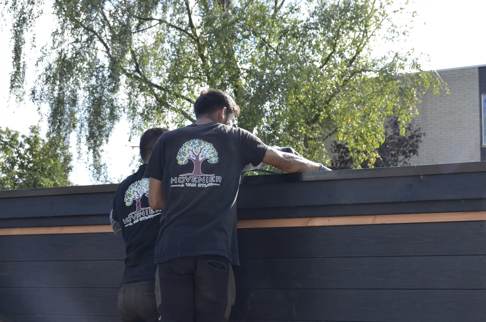 Twee hoveniers werken de dakrand van het tuinhuis af