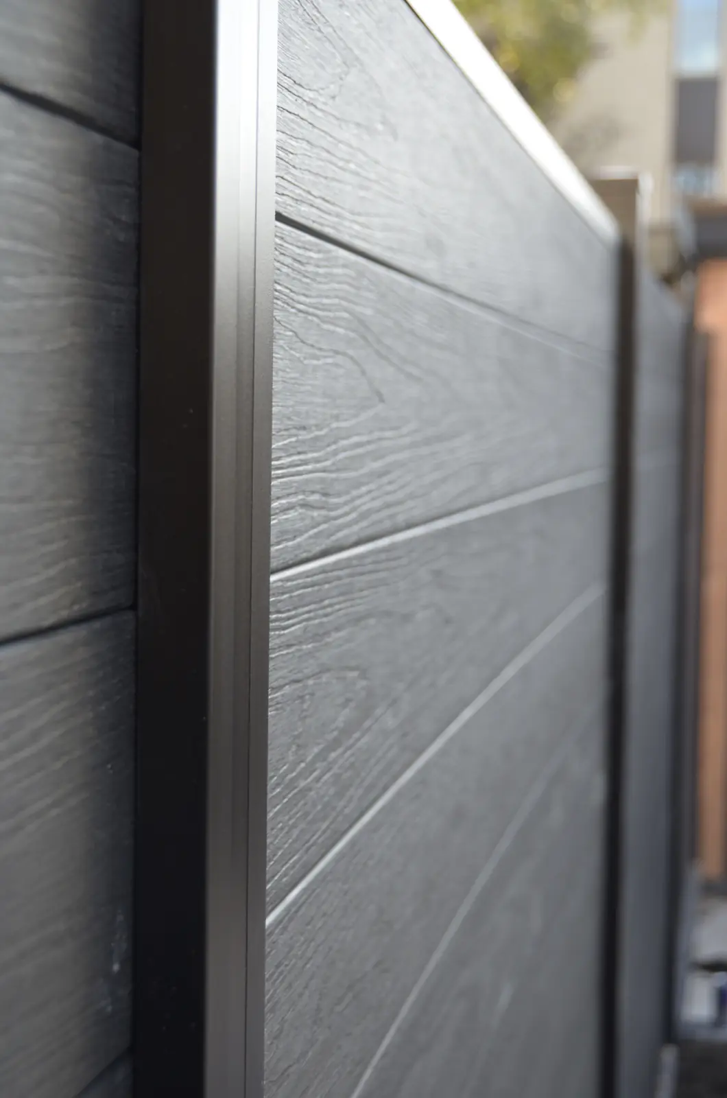 Composiet schutting met houtnerf tussen antraciet aluminium palen