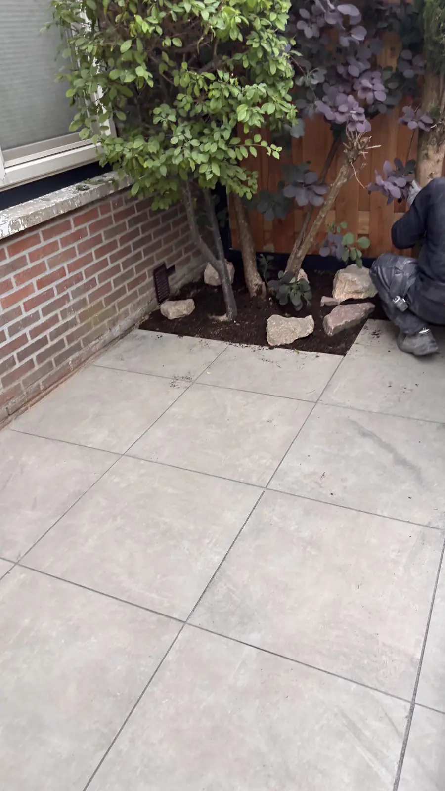 Plantvak met natuursteen in de hoek tussen muur en schutting