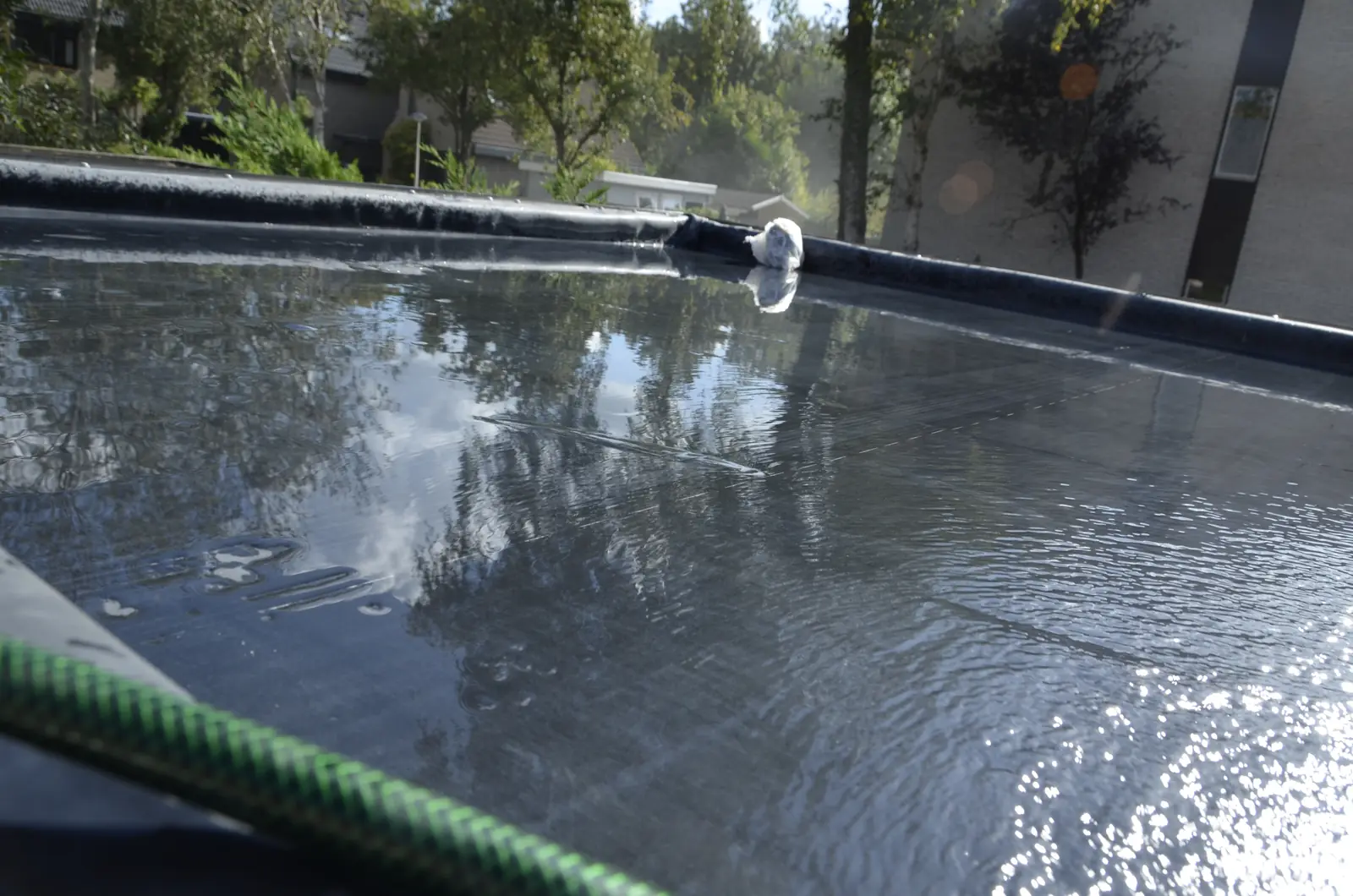 Rubberen dak van het tuinhuis, met de tuinslang onder water gezet