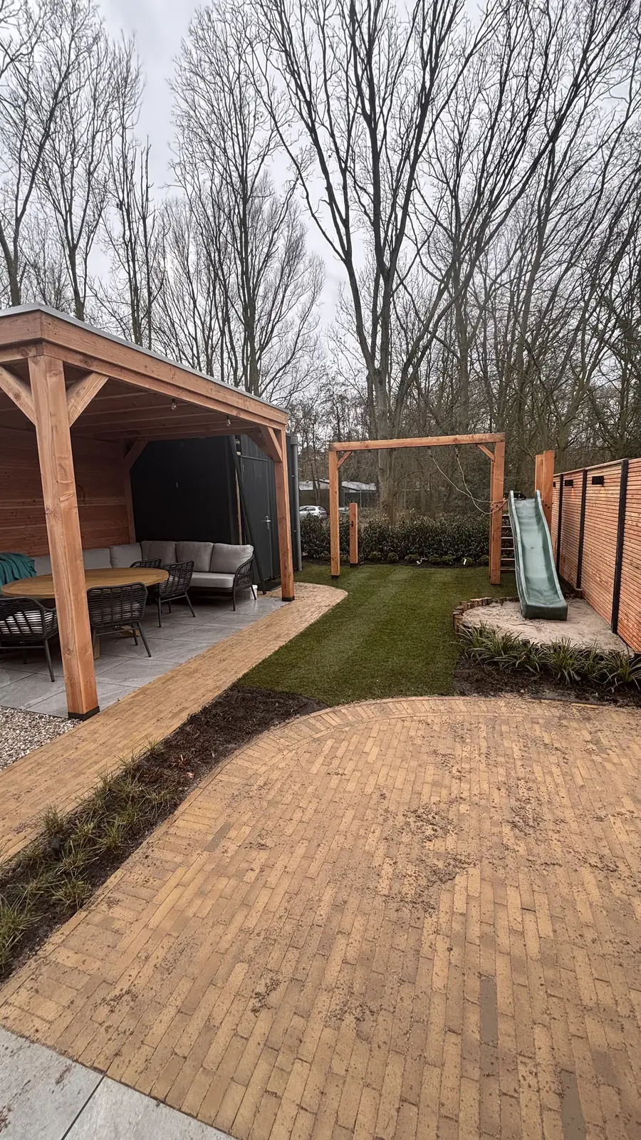 Overkapping met loungehoek naast een pad van gebakken klinkers