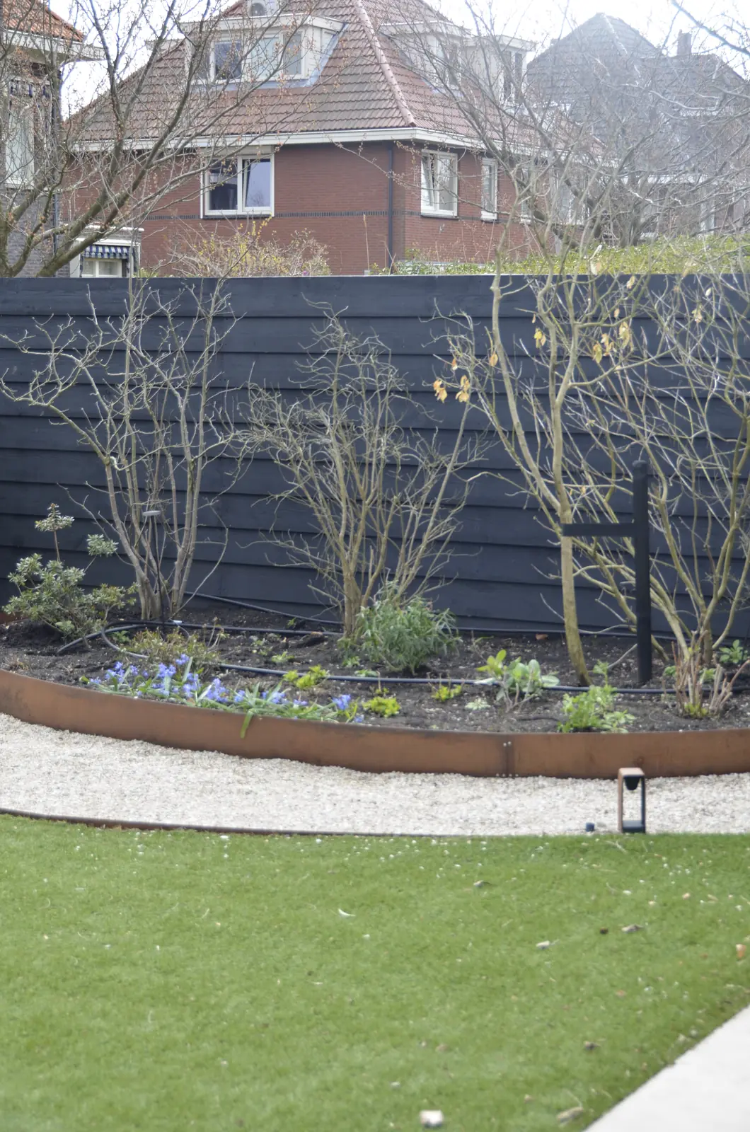 Douglas overkapping naast een ronde border met cortenstalen rand en jonge heesters