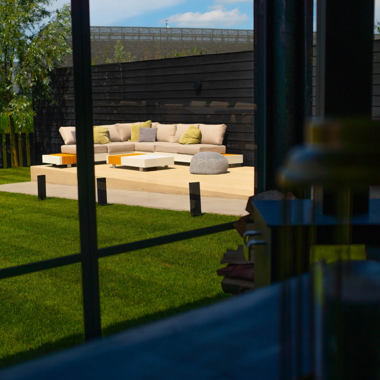 Doorkijk vanuit de veranda over het gazon naar de loungehoek