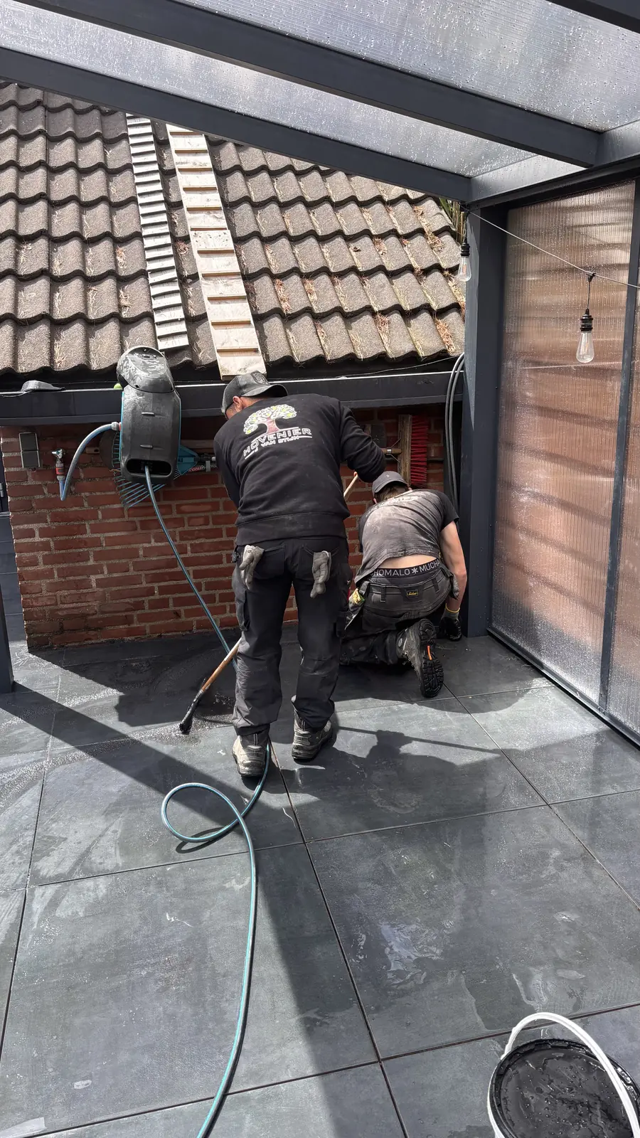 Hovenier werkt bij de gevel onder de veranda