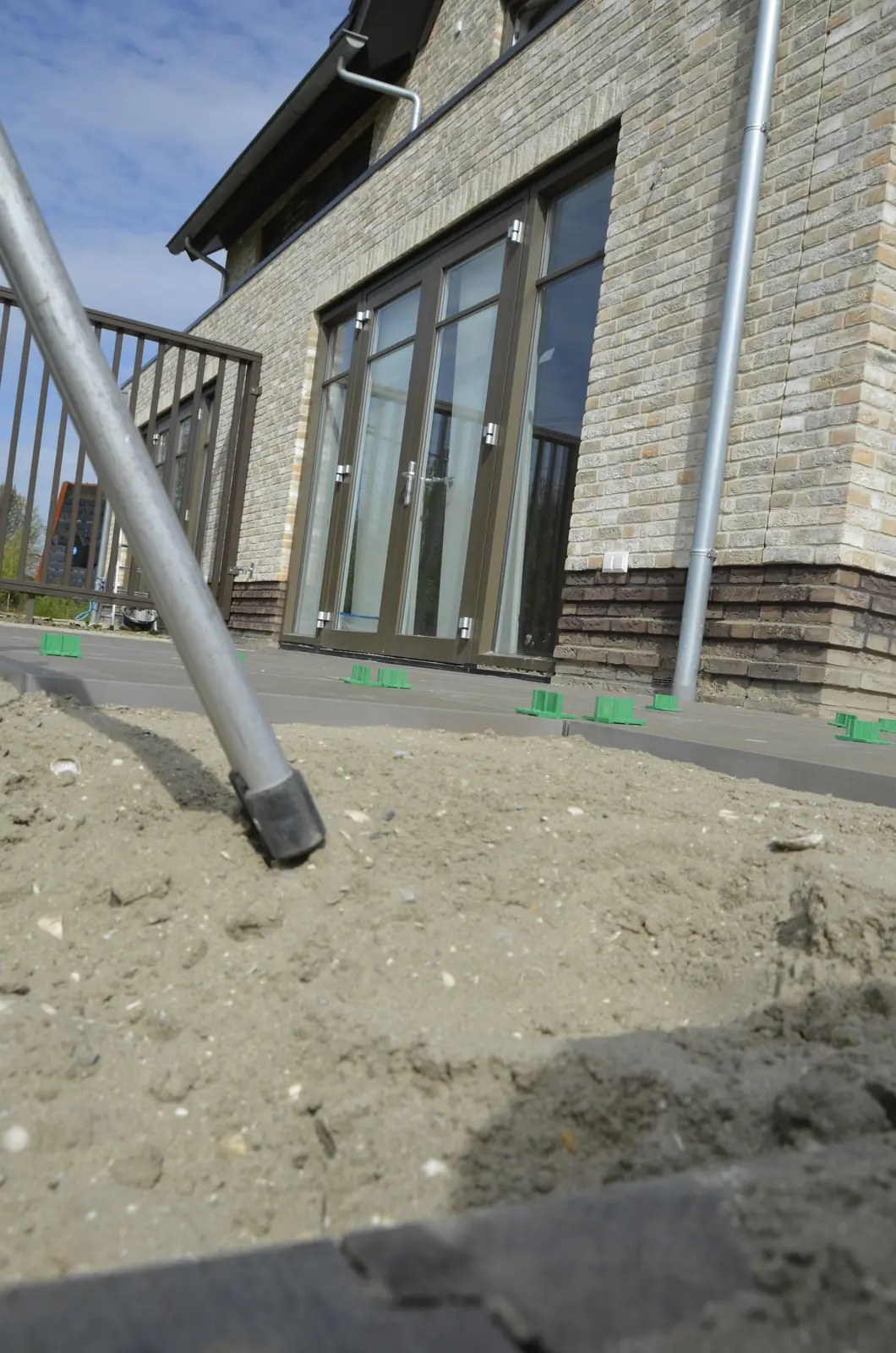 Regenpijp en zandbed langs de gevel