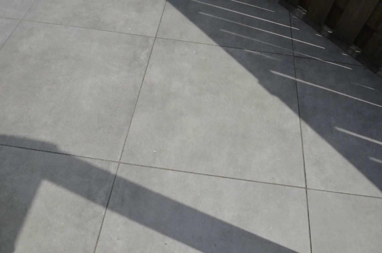 Strak gelegde grijze keramische tegels in de zon