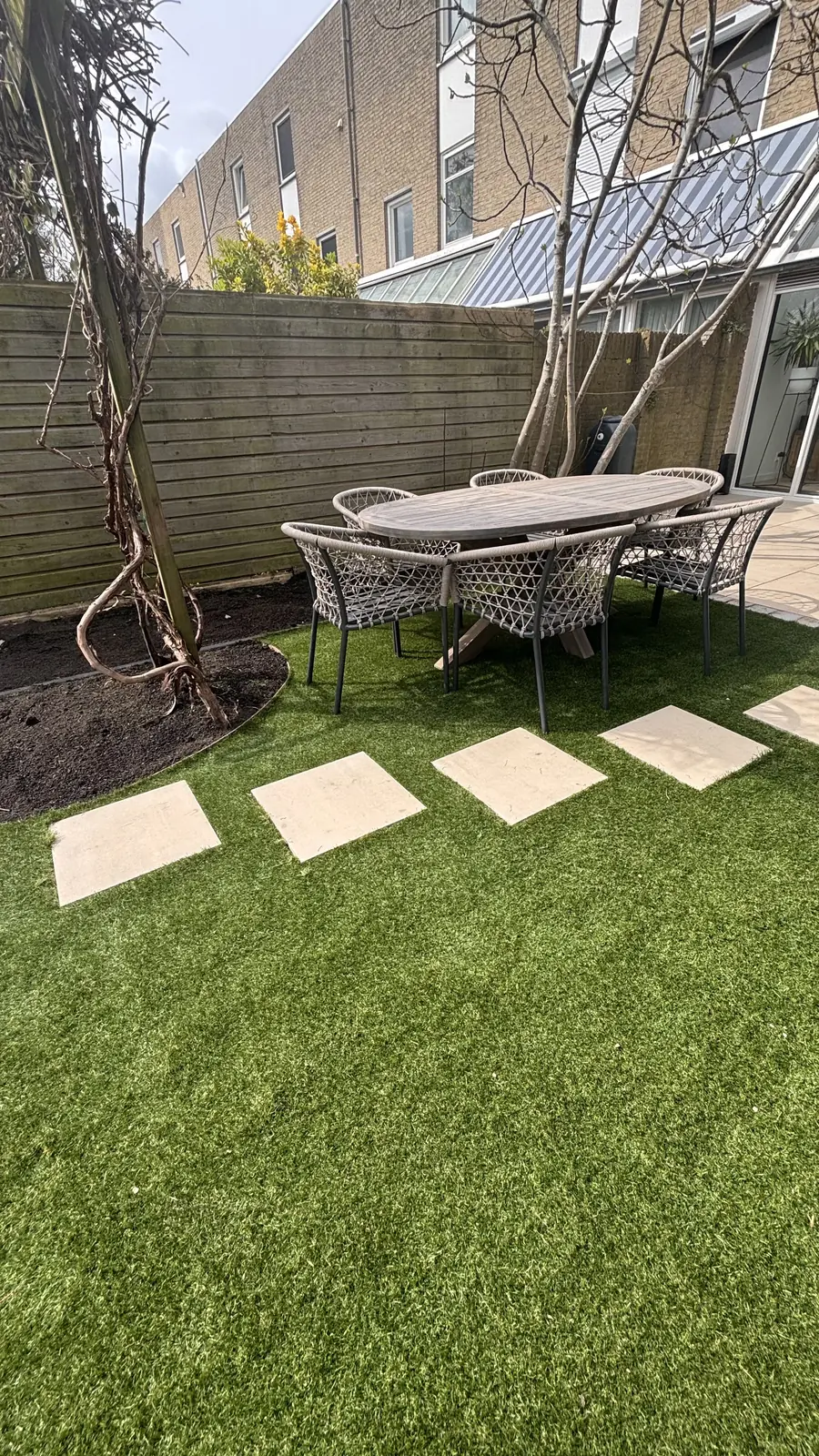 Houten berging achter in de tuin, met stapstenen ernaartoe