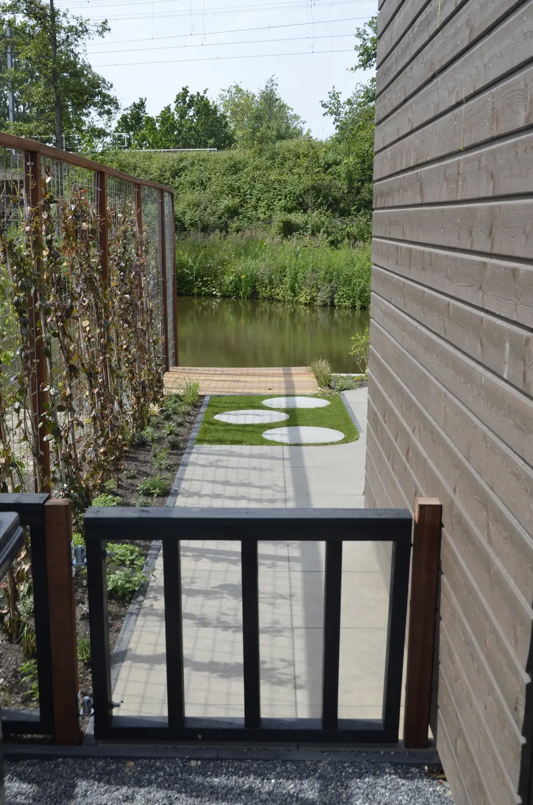 Gazon en terras met het hekwerk naar het water