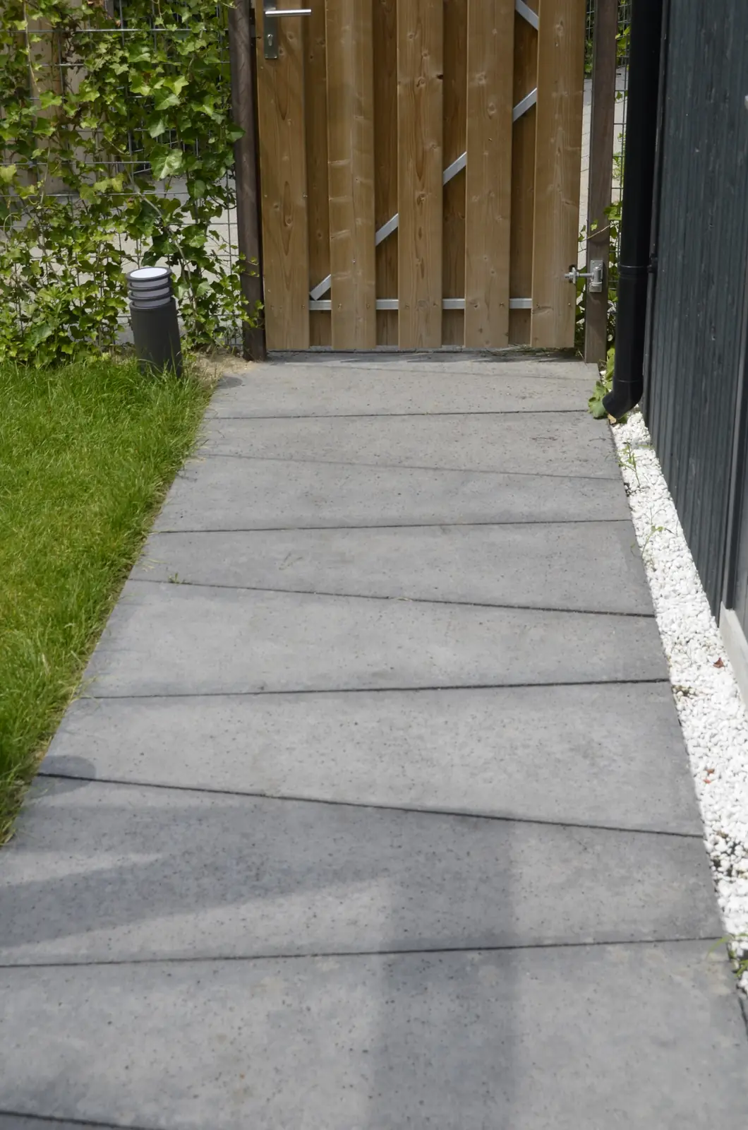 Betonnen looppad naar de houten poort achter in de tuin
