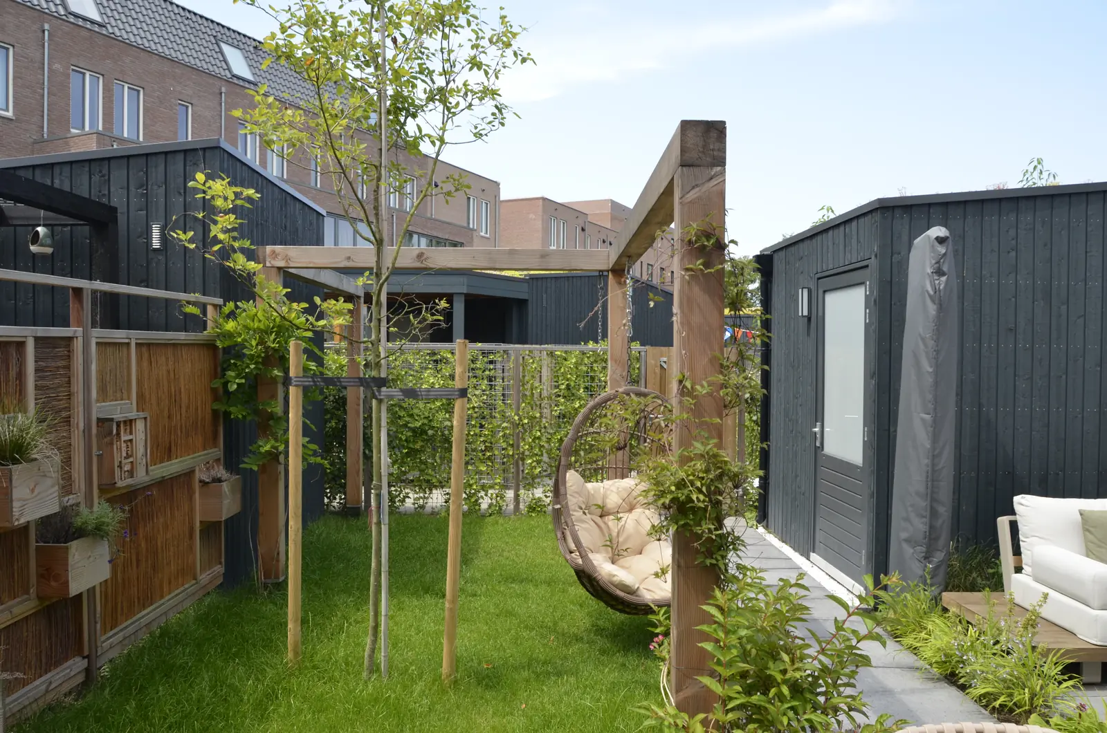 Pergola met hangstoel boven het gazon