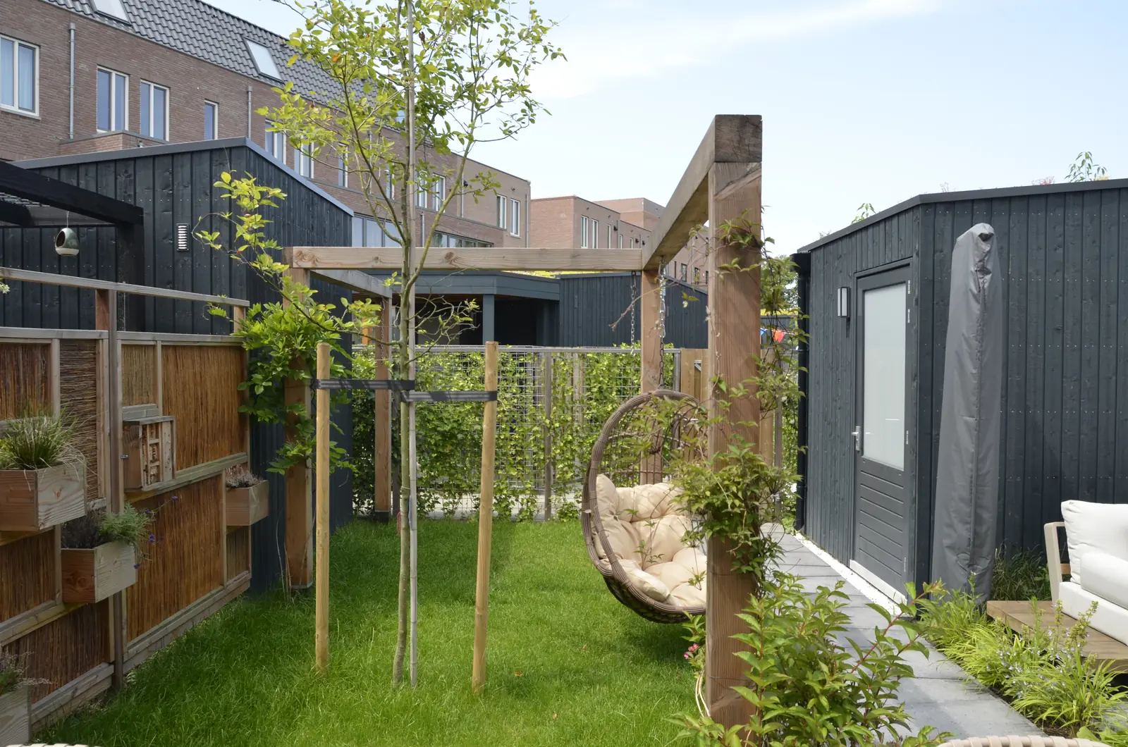 Pergola en houten schermen, met de nieuwbouwwoningen erachter