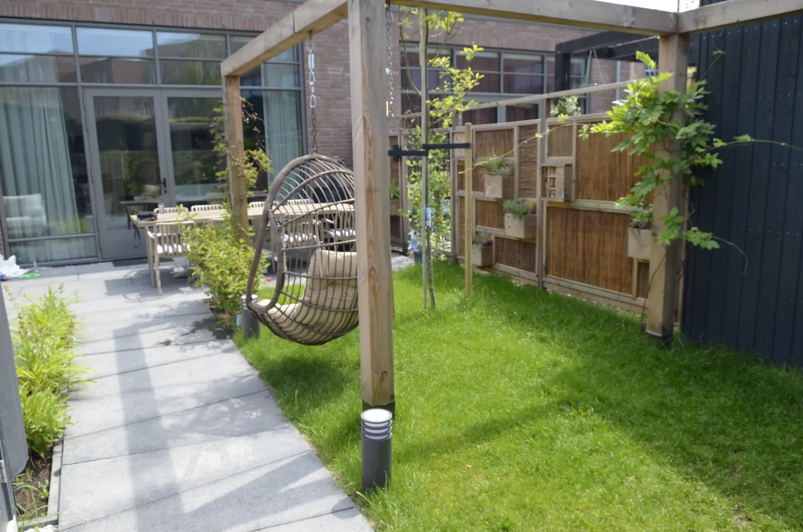 Gazon met pergola en klimplanten langs de erfgrens