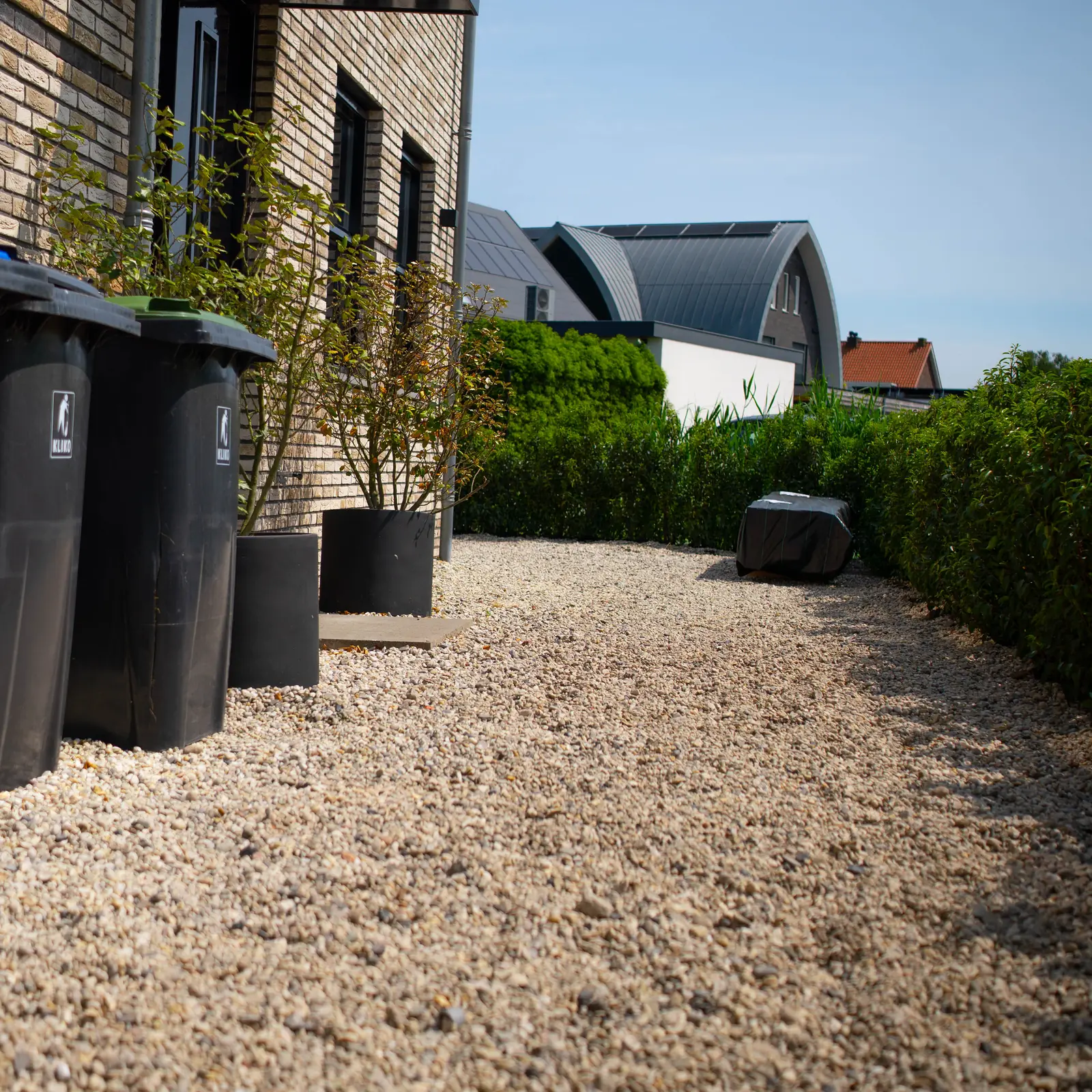Containerplek op grind naast de gevel